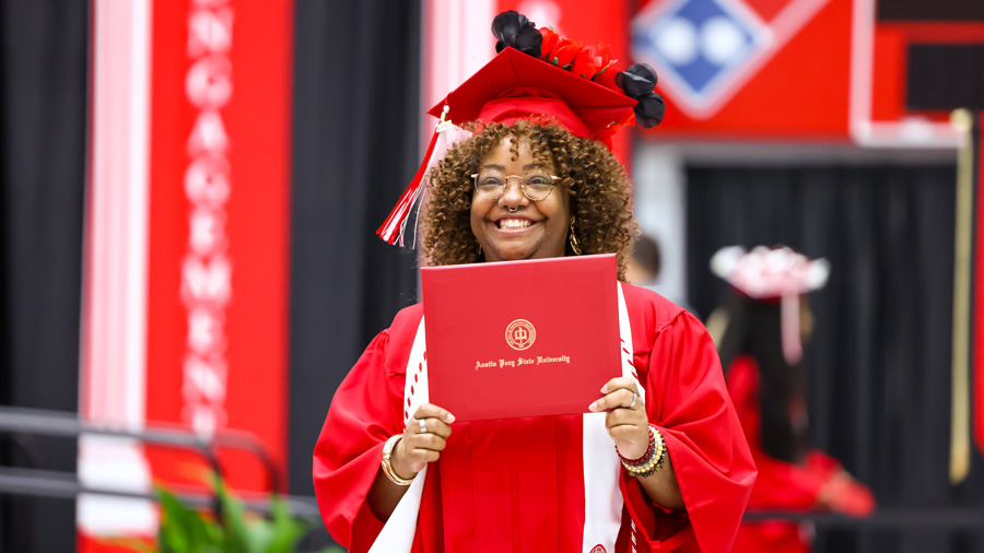 Student holding up their diploma at commencement.